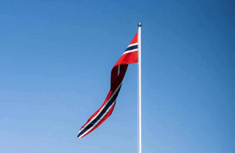 Norsk vimpel på hvit flaggstang mot blå himmel